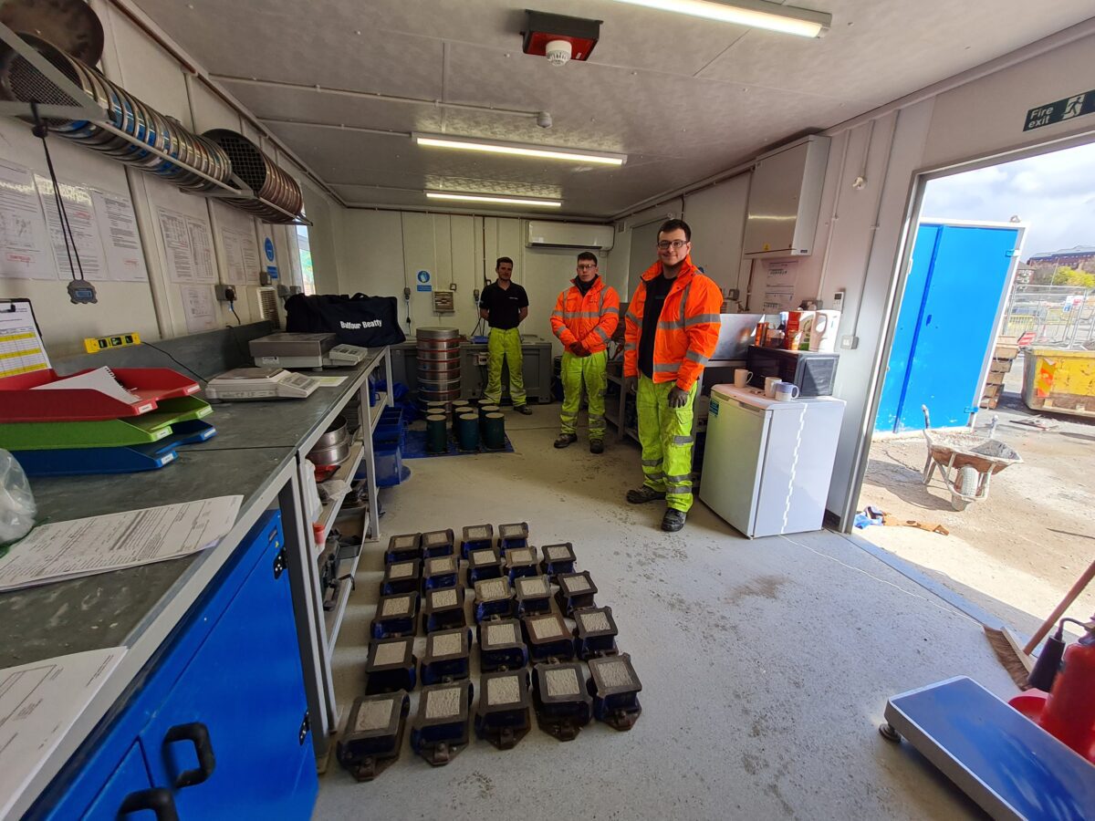 Billy Walton and colleagues, mixing concrete in a temporary workroom, on a building site.
