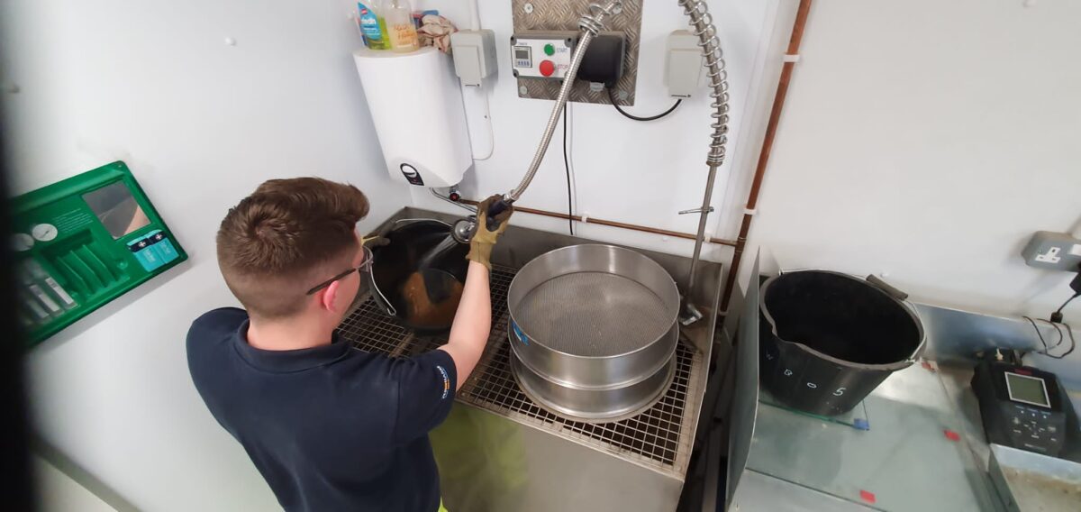 Thomas at a sink, washing out concrete from buckets.