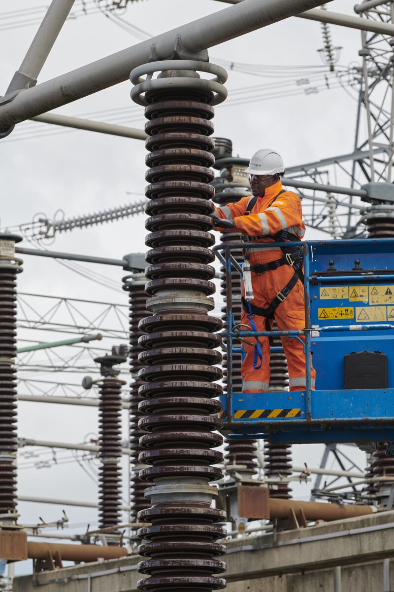 A power network technician doing maintenance in an electrical substation.