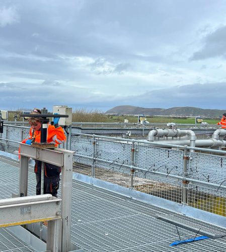 Woman in orange high vis on an industrial water unit