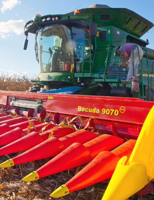 Woman standing on a large agricultural machine in a field.