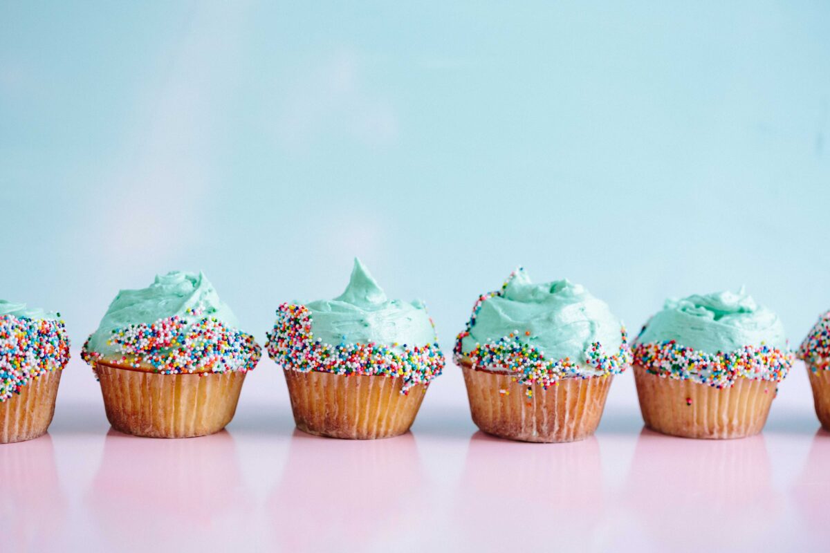 A row of cupcakes, iced, with sprinkles.