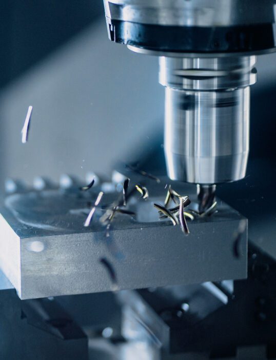 A computer-controlled milling machine carves a component out of a solid block of metal.