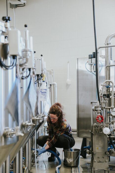 A woman checking brewing vats in a brewery.