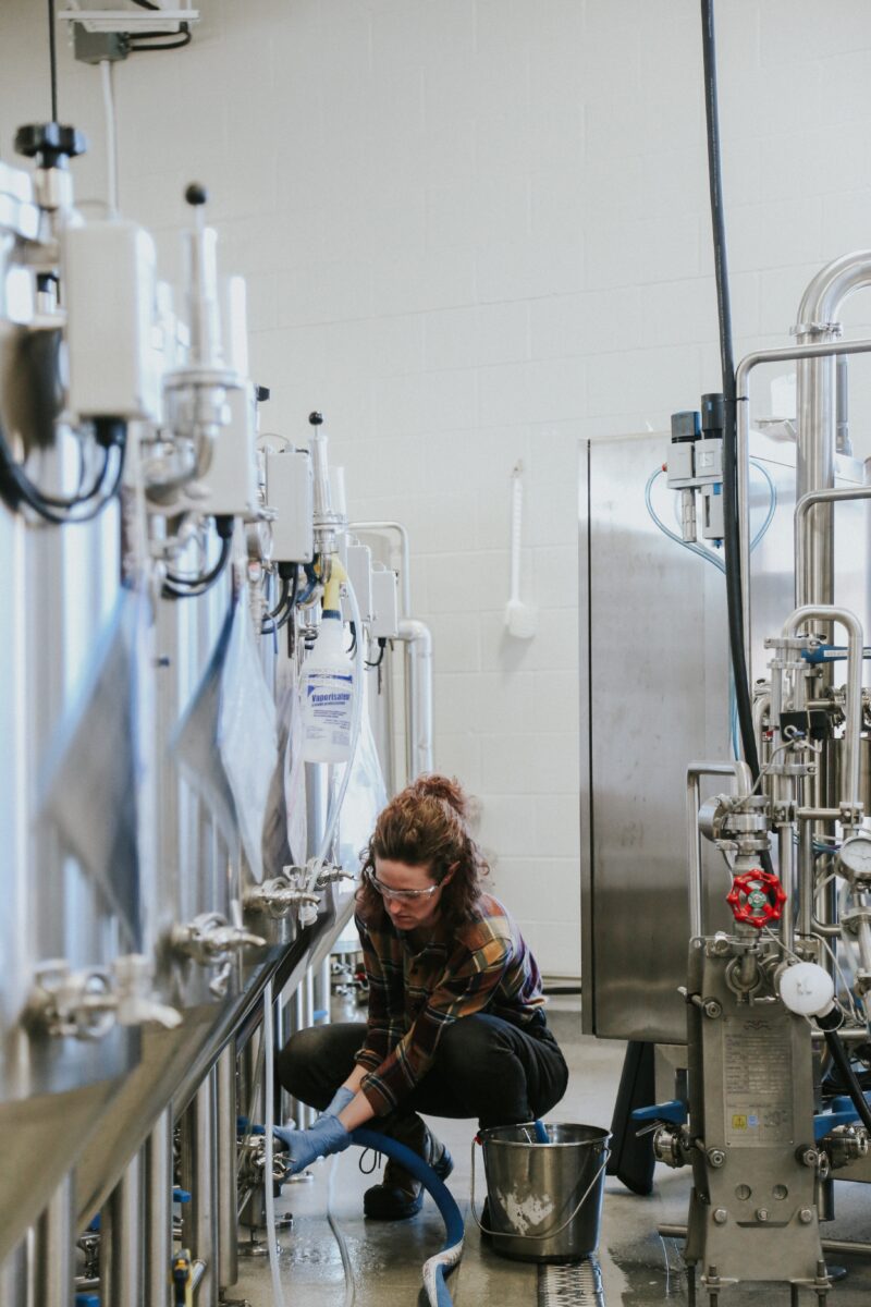 A woman checking brewing vats in a brewery.