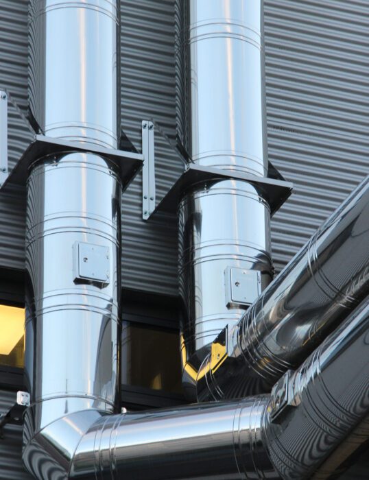 Large pipes running down the exterior of a warehouse.