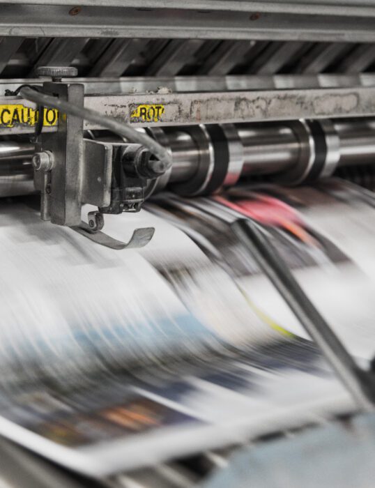 An industrial printer rapidly printing magazine pages.
