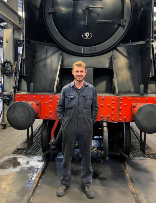 Alex Harper-Bourne standing in front of a steam locomotive.