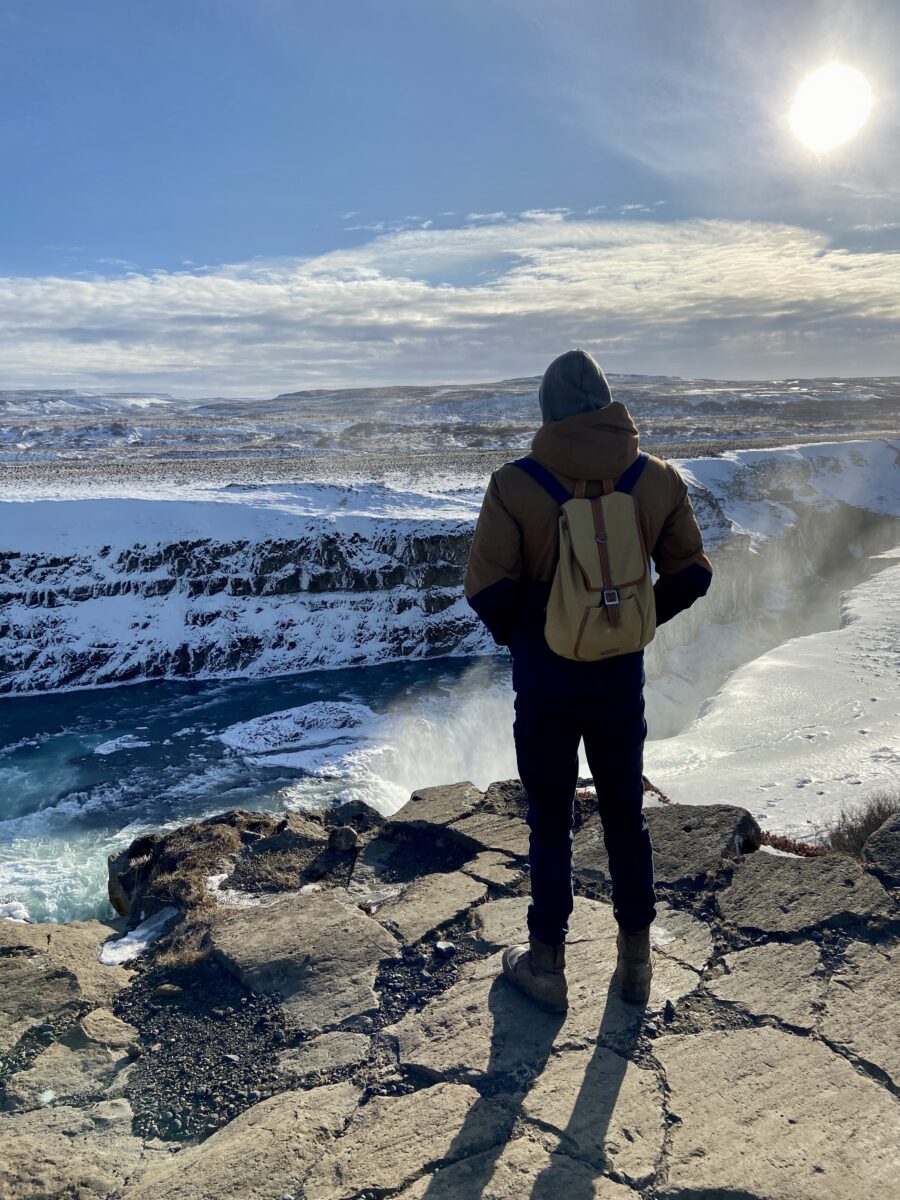 Joe in hiking gear, stood facing an icy landscape.