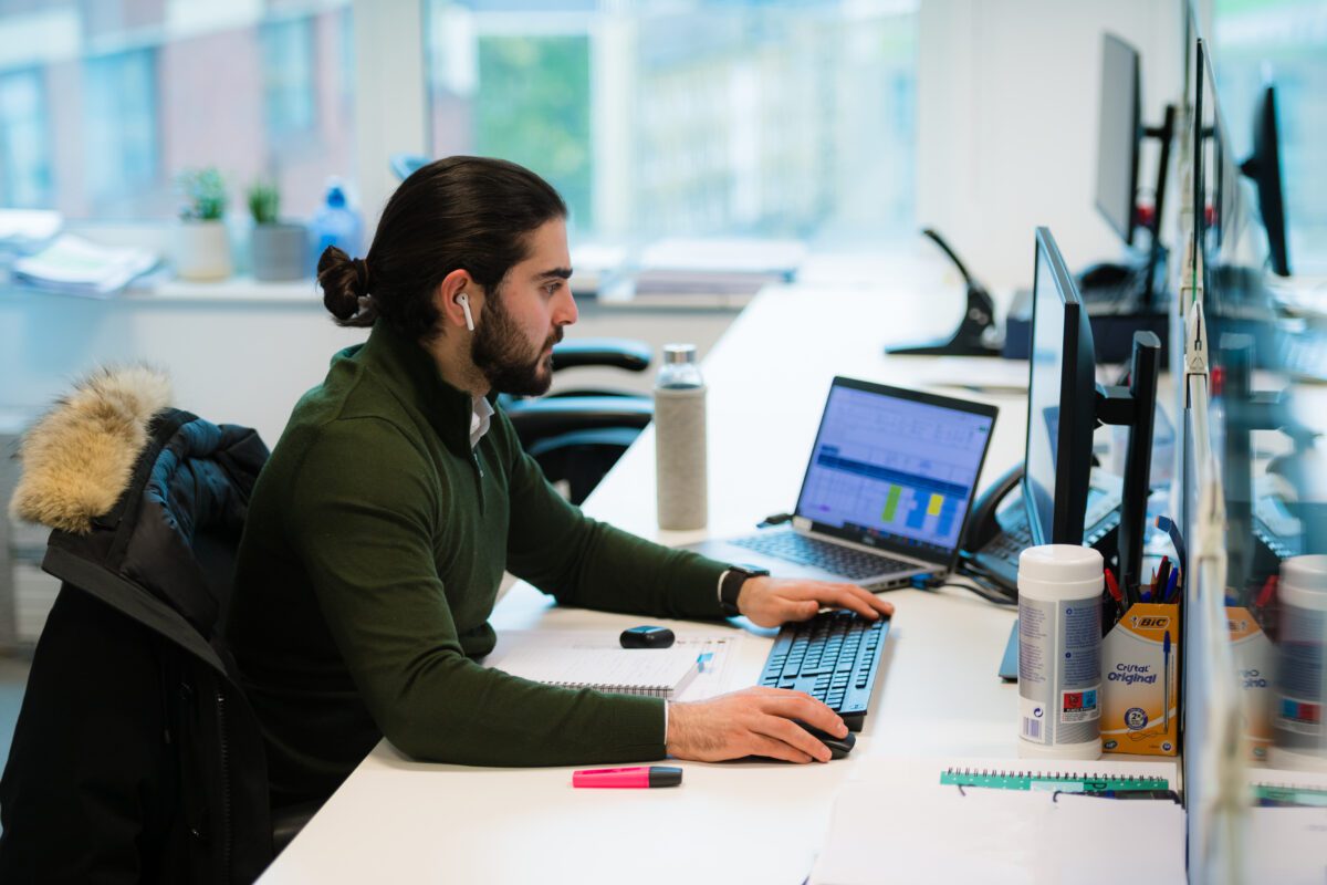Emilio working at his desk, with a laptop and screen.