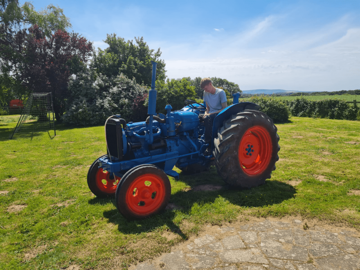 Thomas sitting on a tractor in a field.