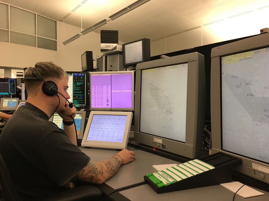 Glen working at his desk, with multiple screens, wearing a headset.