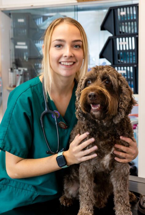Morgan posing in her scrubs, next to a dog.