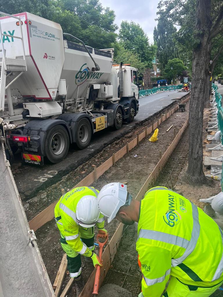 Nuh working with a colleague, digging by the roadside, wearing hi-vis jackets.