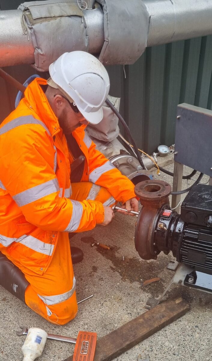 John working at the waste plant, wearing a full hi-vis outfit, hard hat, and safety glasses.