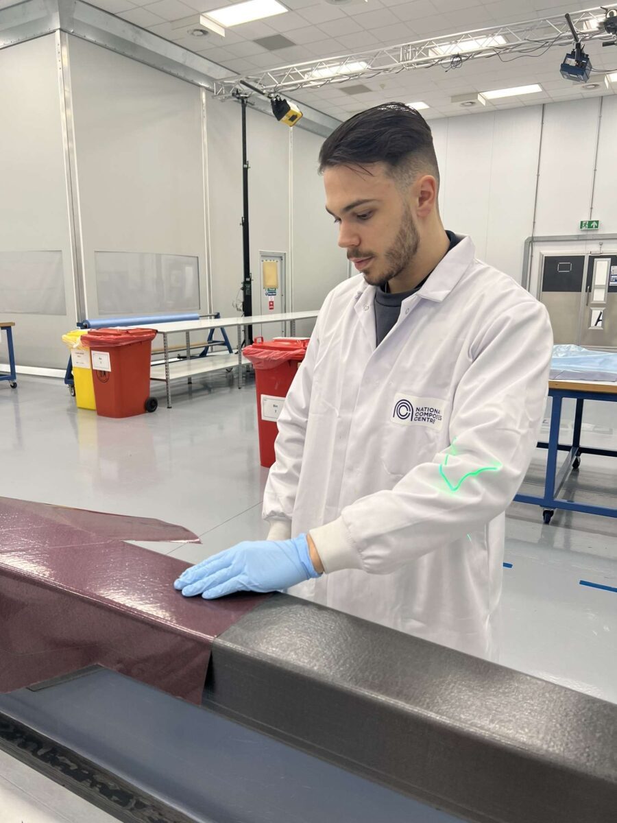 Aidan Church inspecting some newly manufactured material, wearing a lab coat and gloves.
