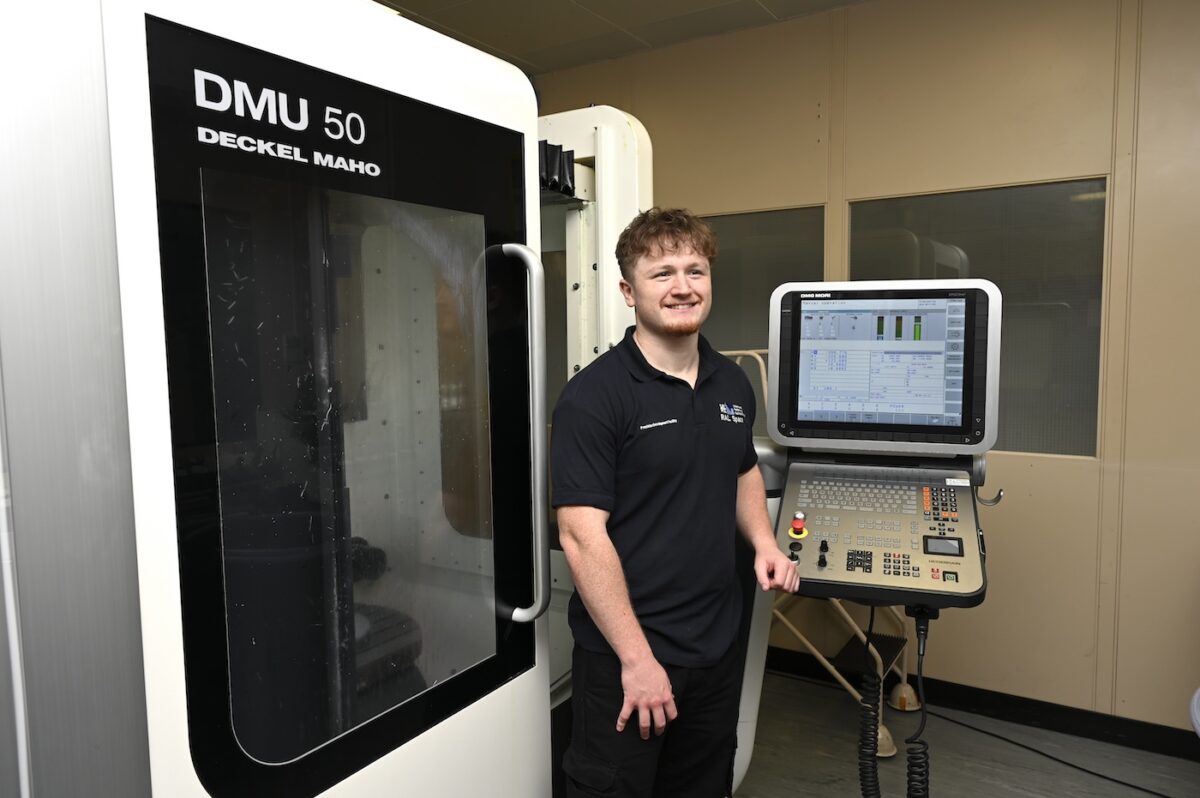 Lucas standing next to an operations console for a large piece of machinery.