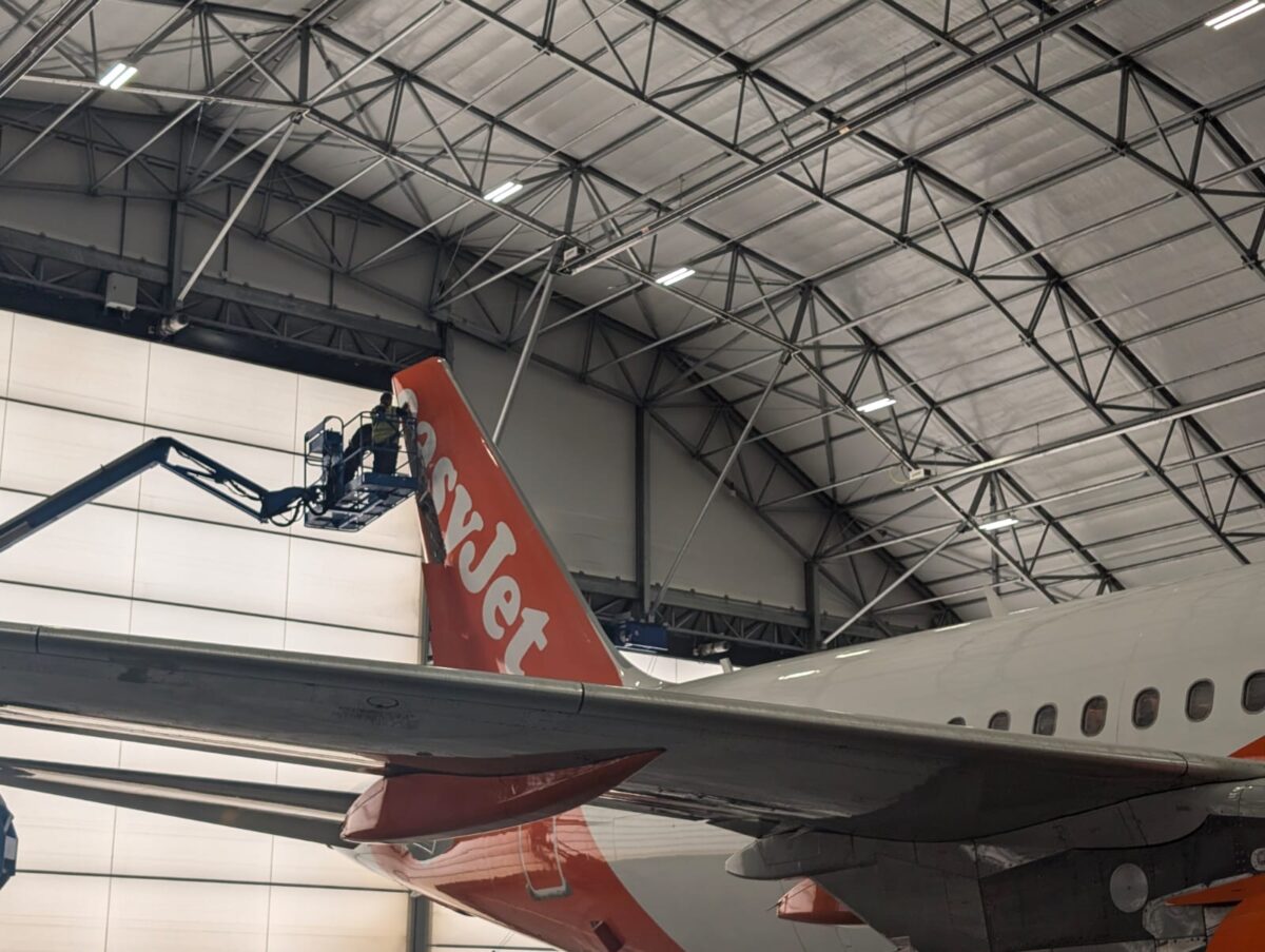 George on a crane, inspecting the tailfin of an EasyJet plane.