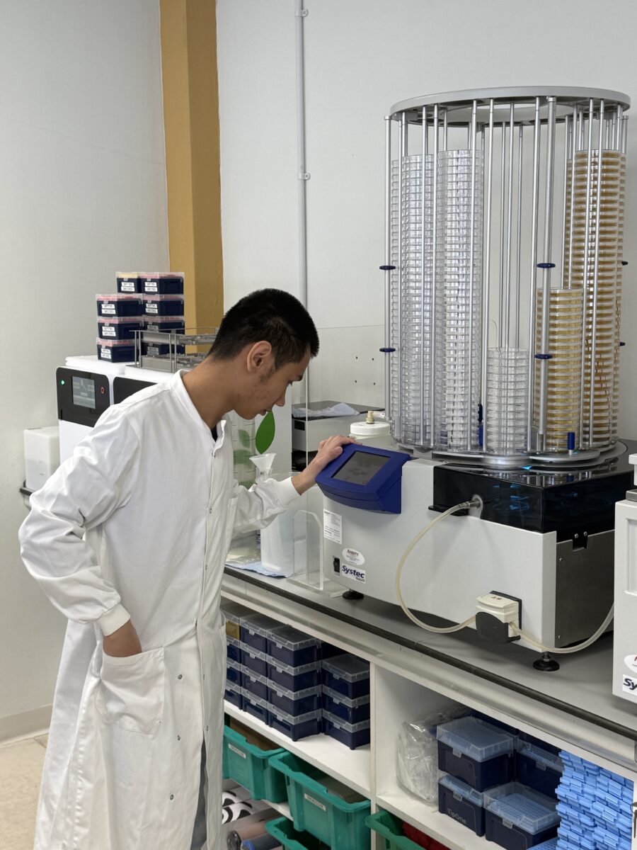 Francis Aclan wearing a lab coat, working on another piece of machinery in the lab.