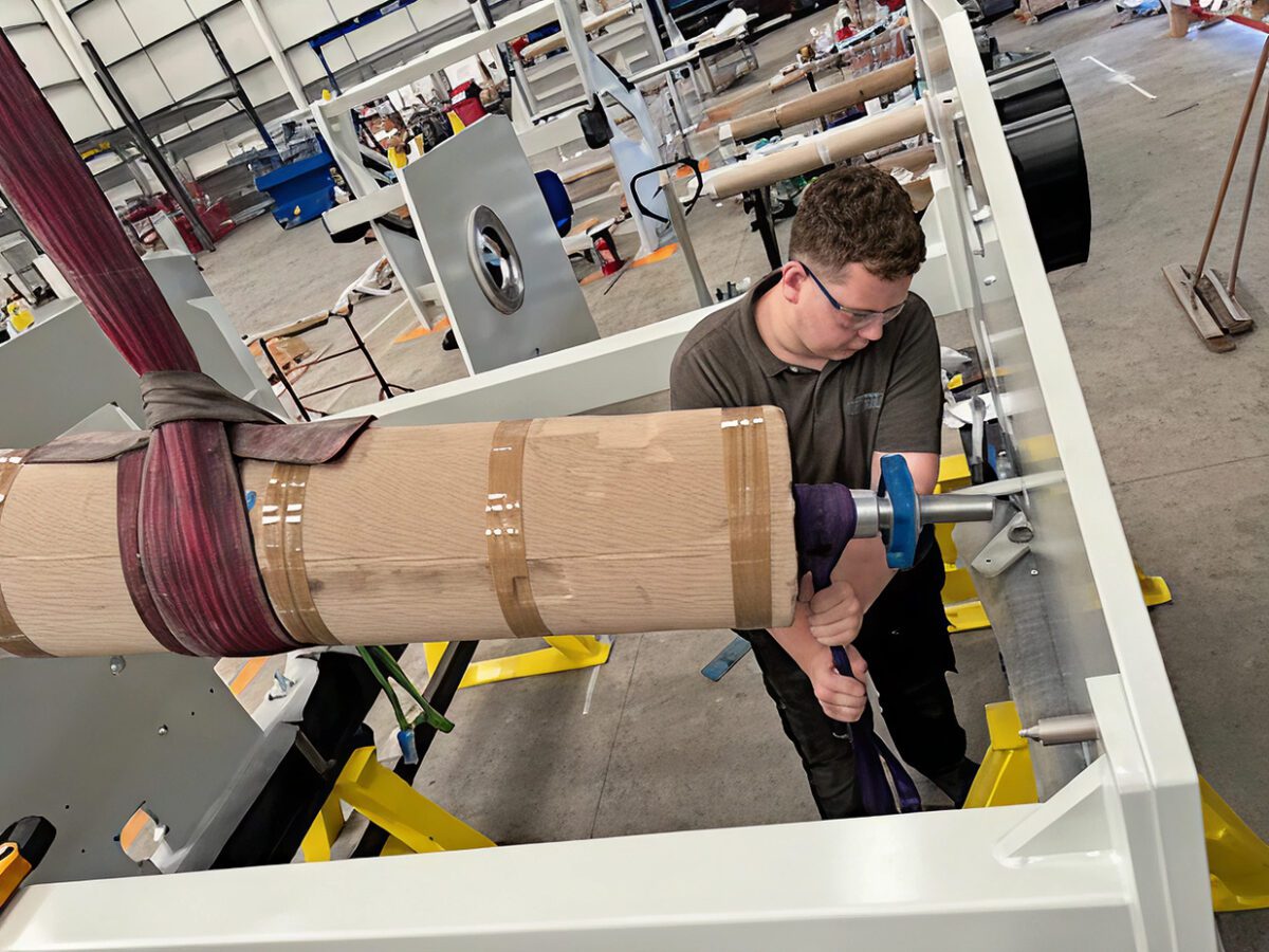 Ben working on the workshop floor, using a piece of equipment and wearing safety goggles.