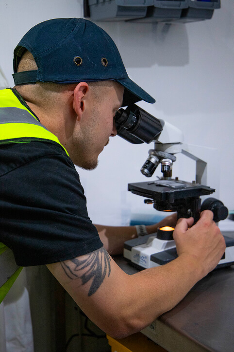 Max looking down a microscope at a sample.