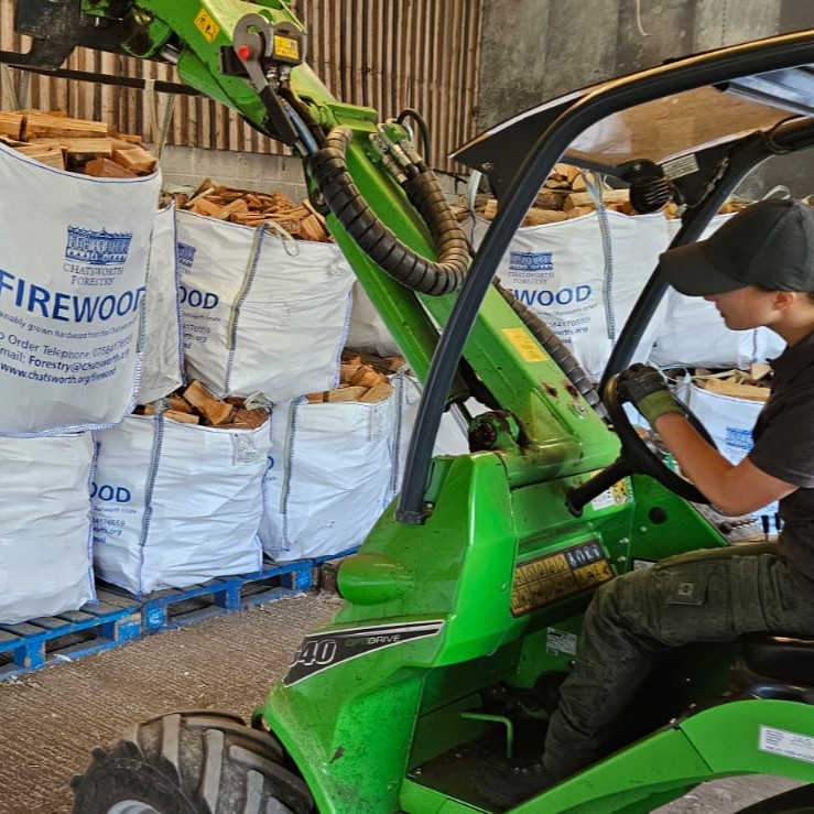 Matilda driving an Avant, using the crane to move large bags of logs.
