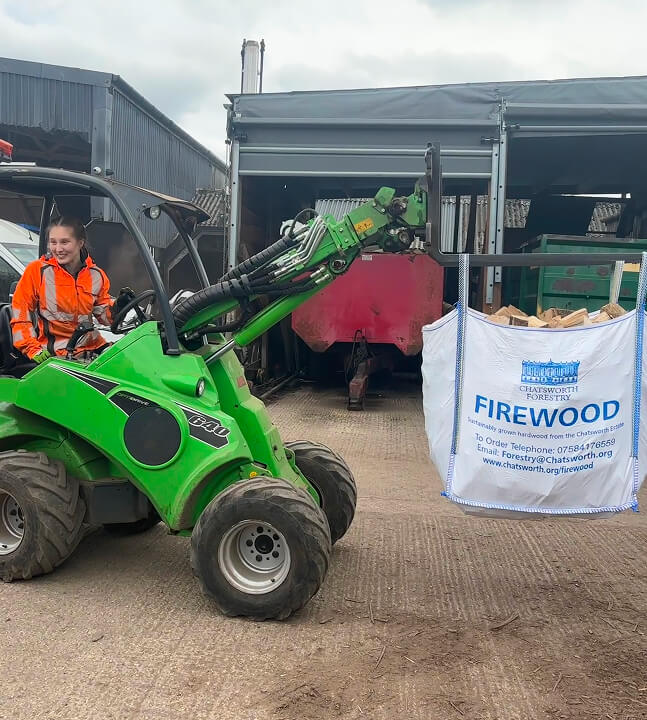 Tree and Forestry Technician Matilda, driving a vehicle like a craned fork lift truck, transporting a large bag of logs.