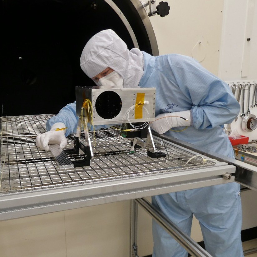 Louis wearing a full clean suit including a face mask, putting components together.