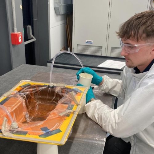 Sam wearing a protective suit, gloves and goggles, about to cast a mould.