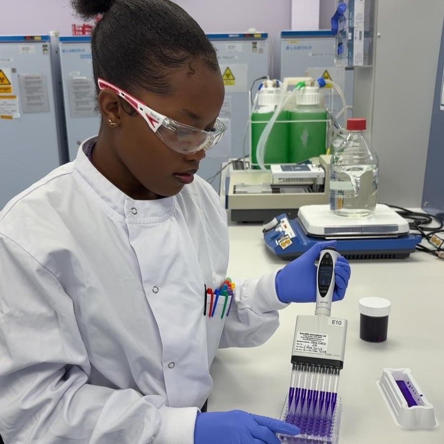 Dudzai in the lab, wearing a lab coat, safety goggles, and a pair of nitrile gloves, preparing some samples.
