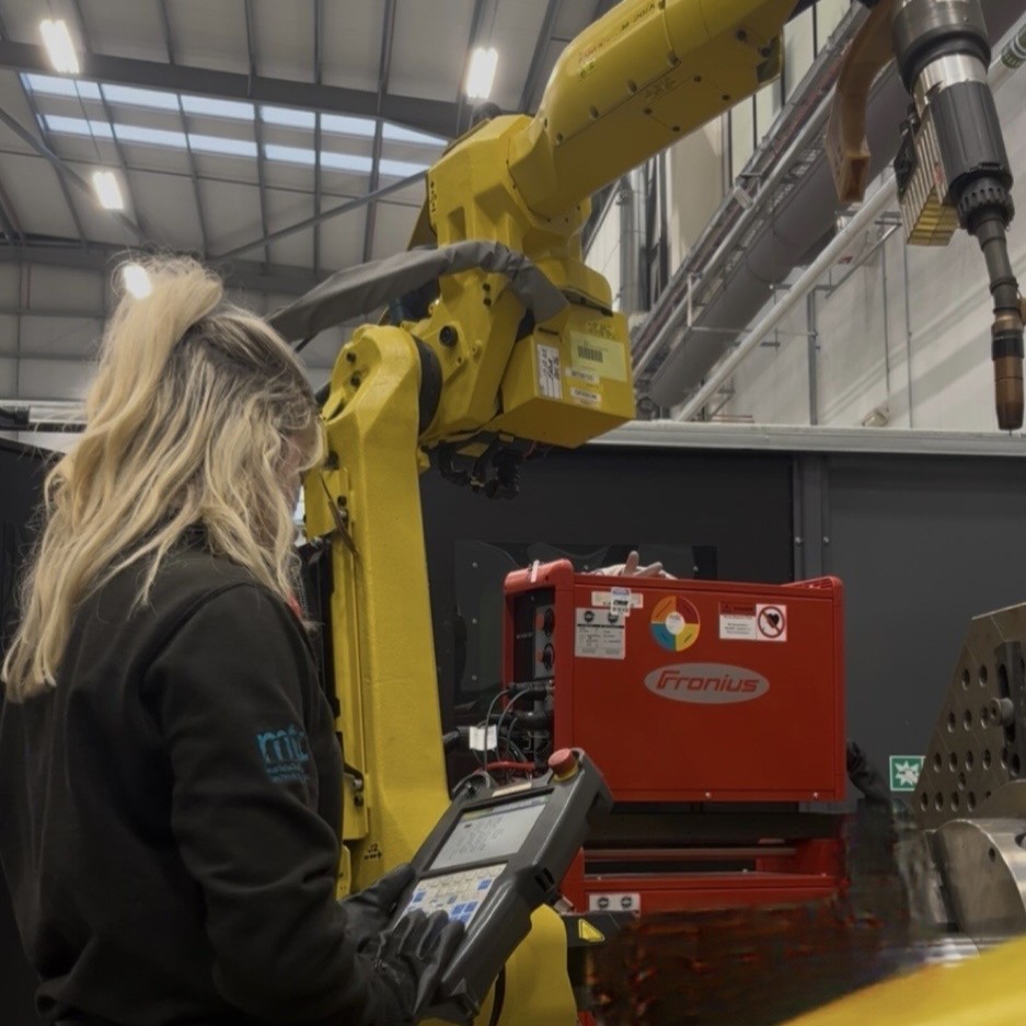 Lily programming a robot arm, using a hand-held terminal.