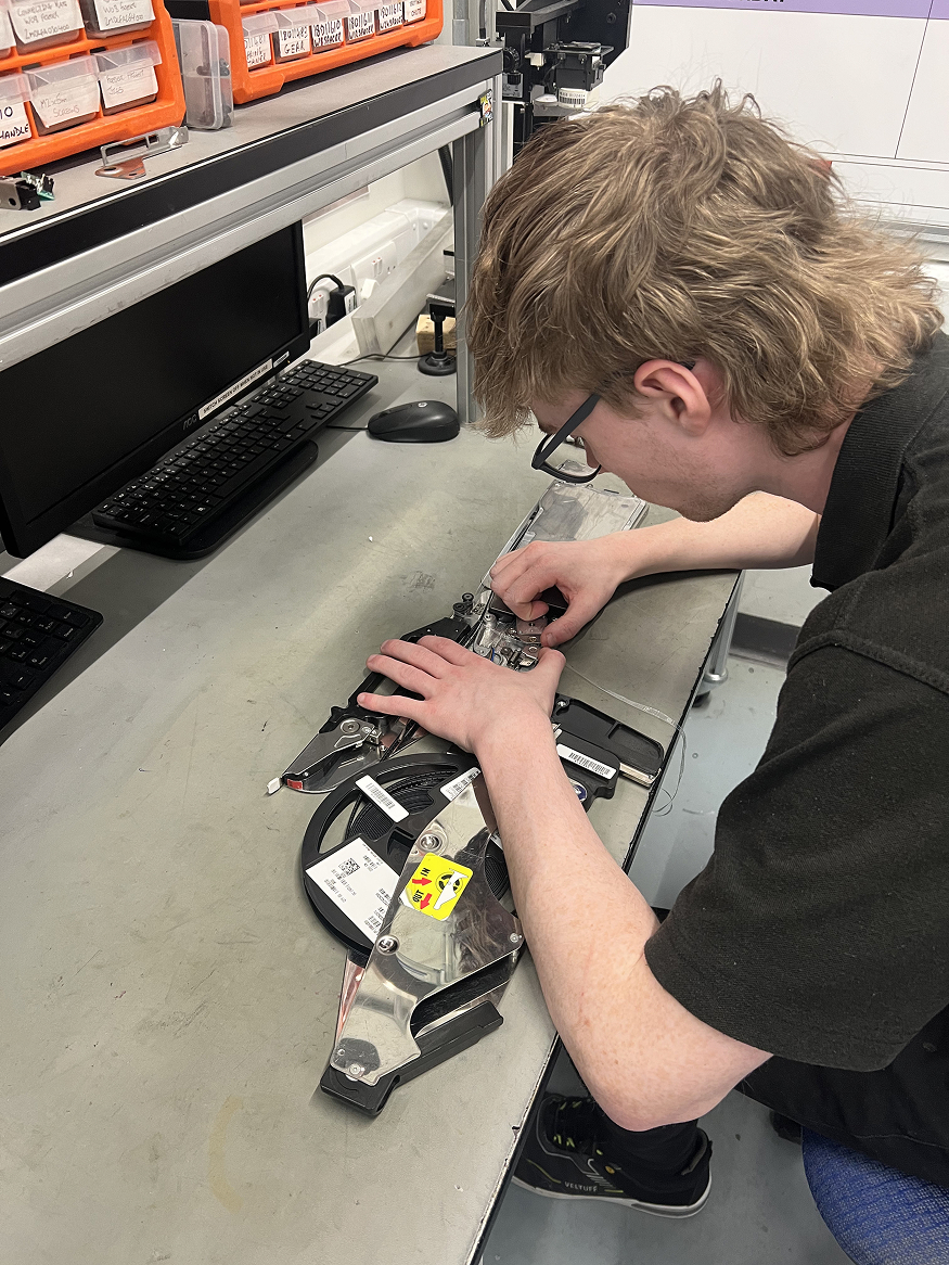 A man facing down on a work bench working on a piece of equipment