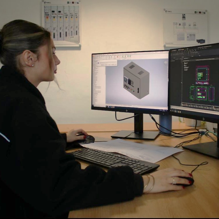 Engineering Fitter Imogen, sat at a desk with two computer screens, using AutoCAD software.