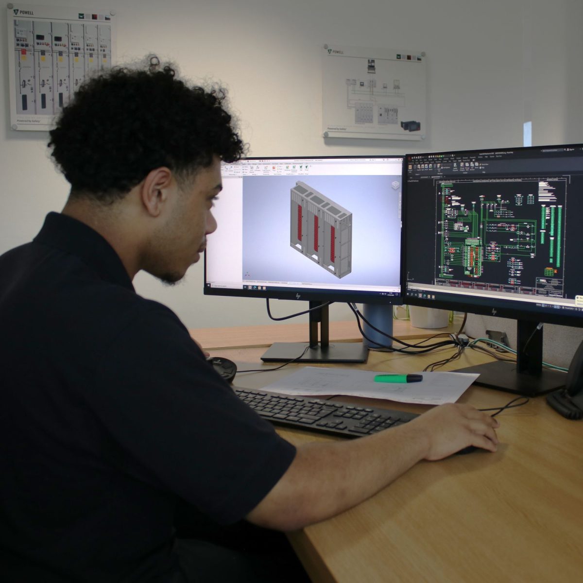 Electrical Engineering Technician Micah, sat at a desk with two screens, using AutoCAD software.