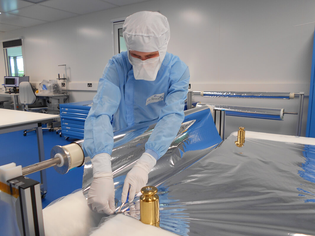 A man in a medical grade PPE using a scalpel to cut some foil like material