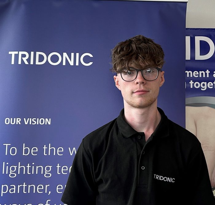 A man standing facing the camera in front of a work banner for Tridonic