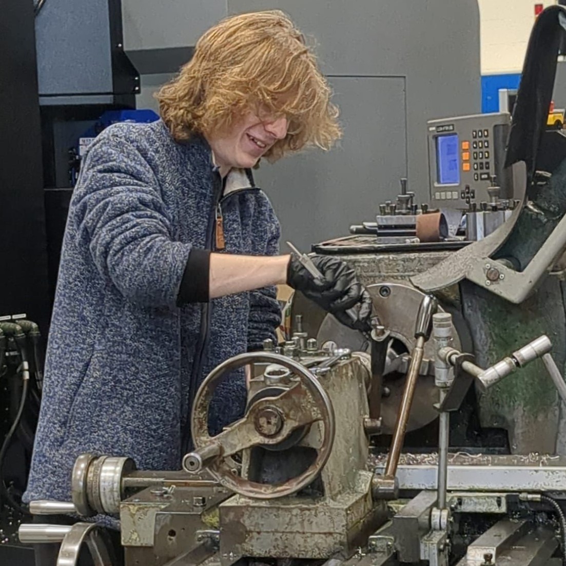 Maintenance and Operations Engineering Technician Ben, wearing latex gloves, using a tool to fix a machine.