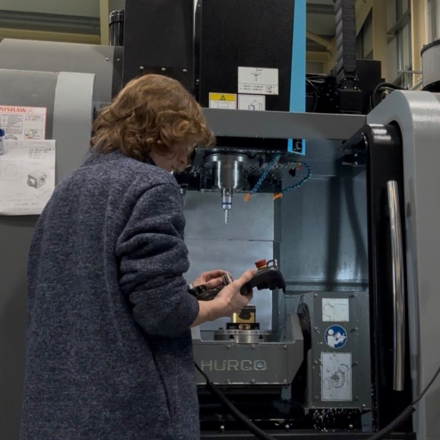 Maintenance and Operations Engineering Technician Ben, stood next to a large industrial CNC milling machine.