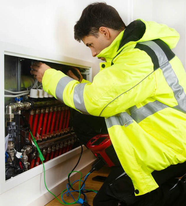 A mean working inside wearing a yellow hi-vis rain coat.