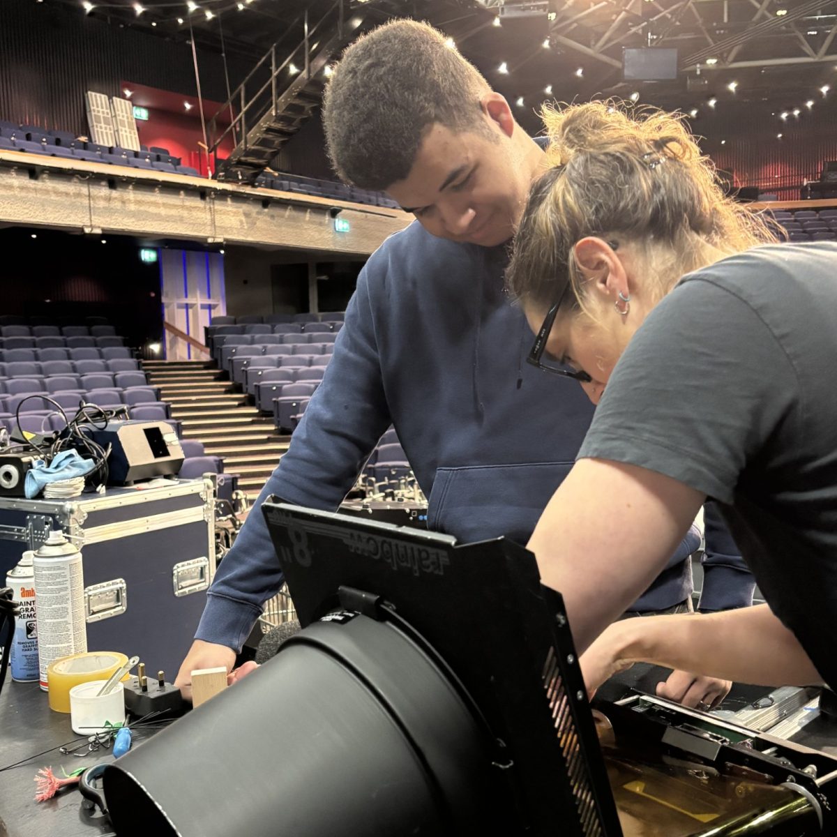 Creative Venue Technician Hugo, working with a colleague in an empty auditorium, fixing a stage light.