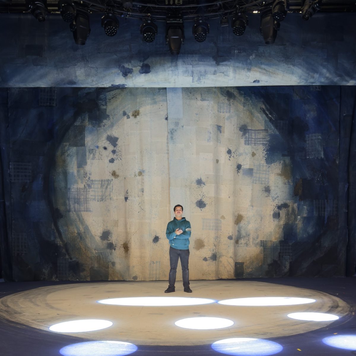 Creative Venue Technician Hugo, stood on an empty stage, checking the direction of spotlights.