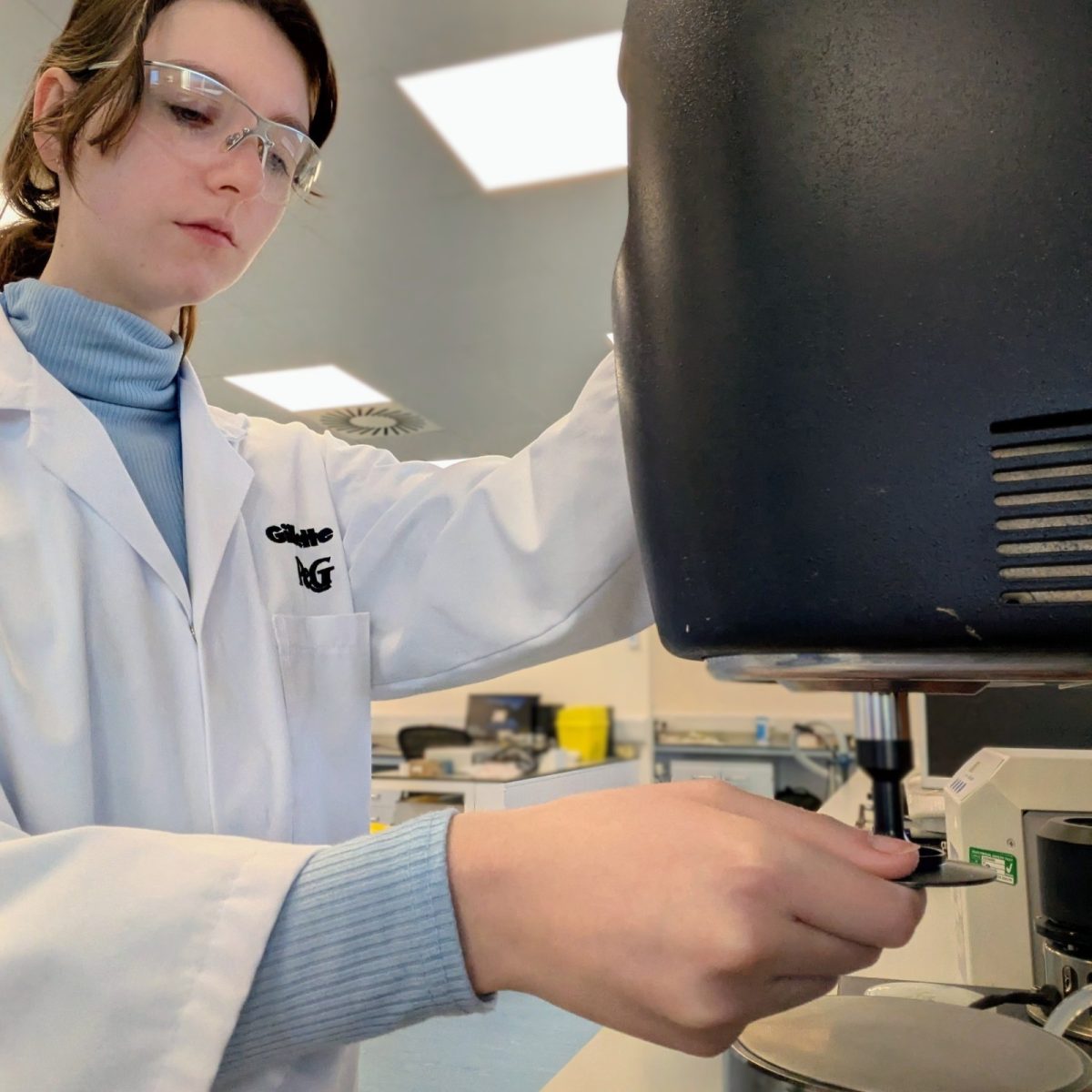 Research Laboratory Technician Jorja in the lab, wearing a lab coat and protective glasses, using a rheometer.