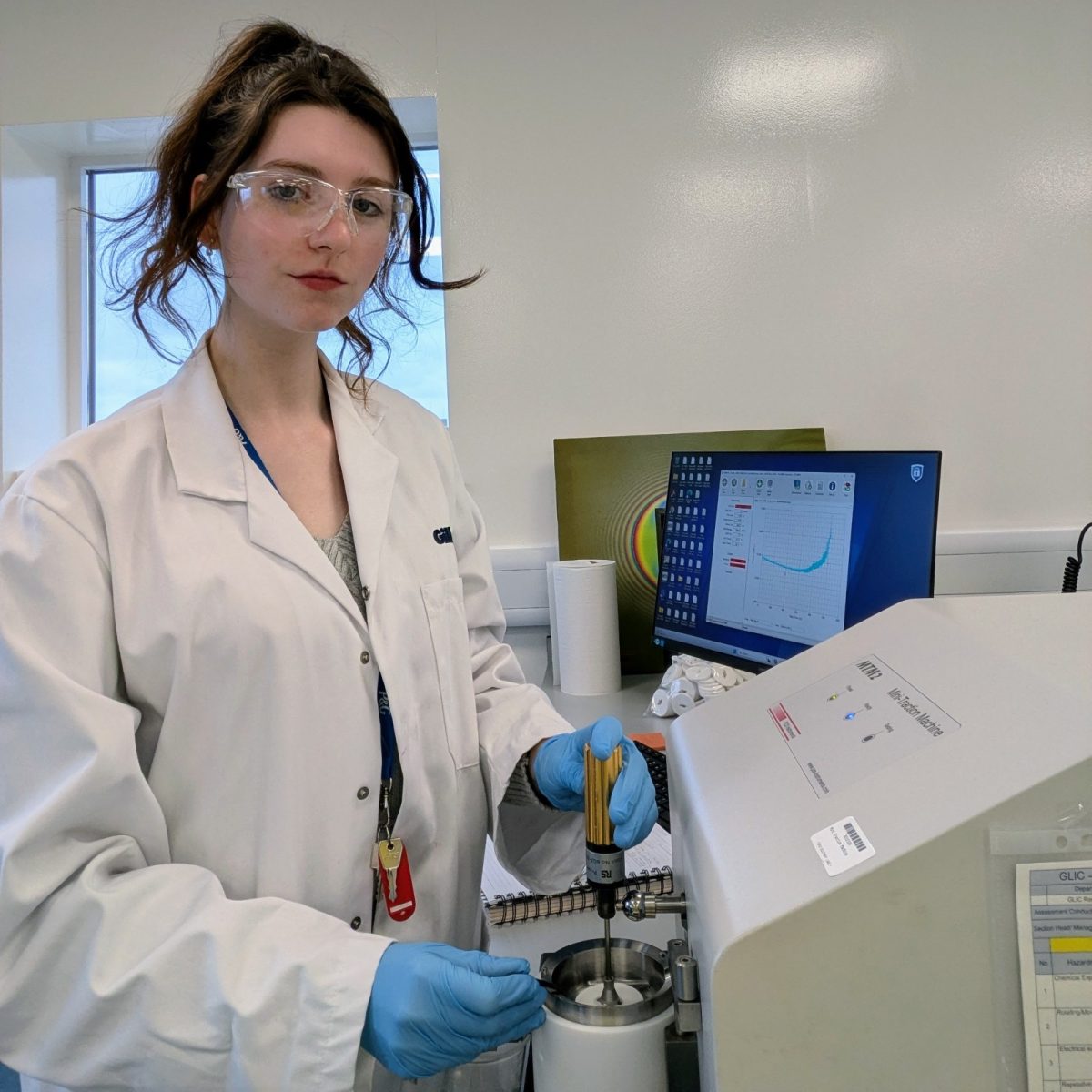 Research Laboratory Technician Jorja in the lab, wearing a lab coat and protective glasses, using a mini traction machine.