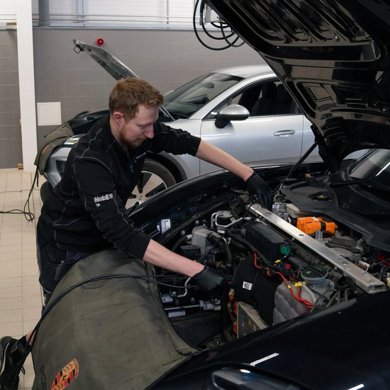 Electric Vehicle Technician Pete, working under the hood of a car, in the garage.