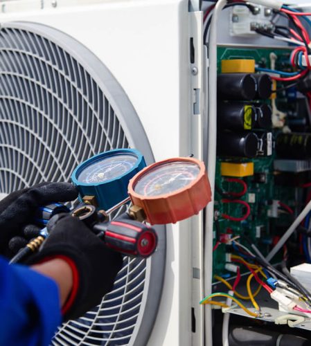 A pair of hands holding a gauge attached to a external fan unit.
