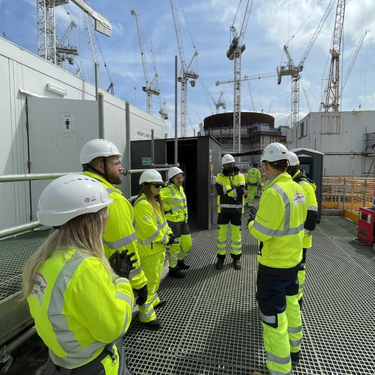 Data Technician Letty stood with colleagues on site, dressed in hi-vis overalls, hard hats and safety glasses.