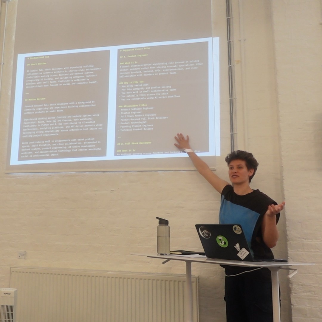 Software Developer Jaz, standing at a lectern, giving a talk, gesturing to code projected onto the wall.