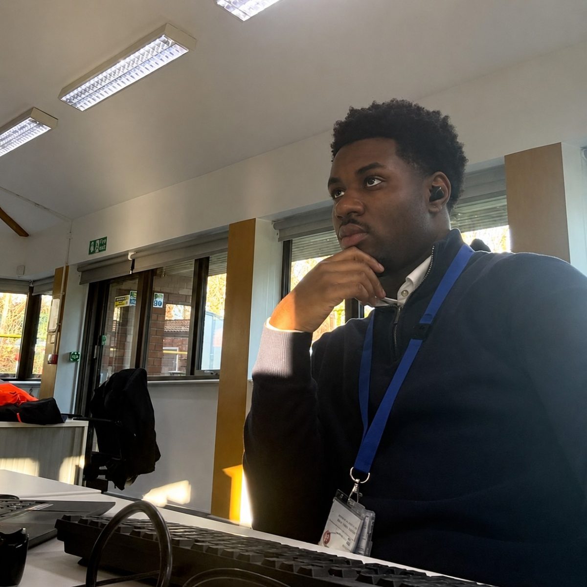 Civil Engineering Technician Tochi, wearing a fleece, sat at his desk, working on his computer.
