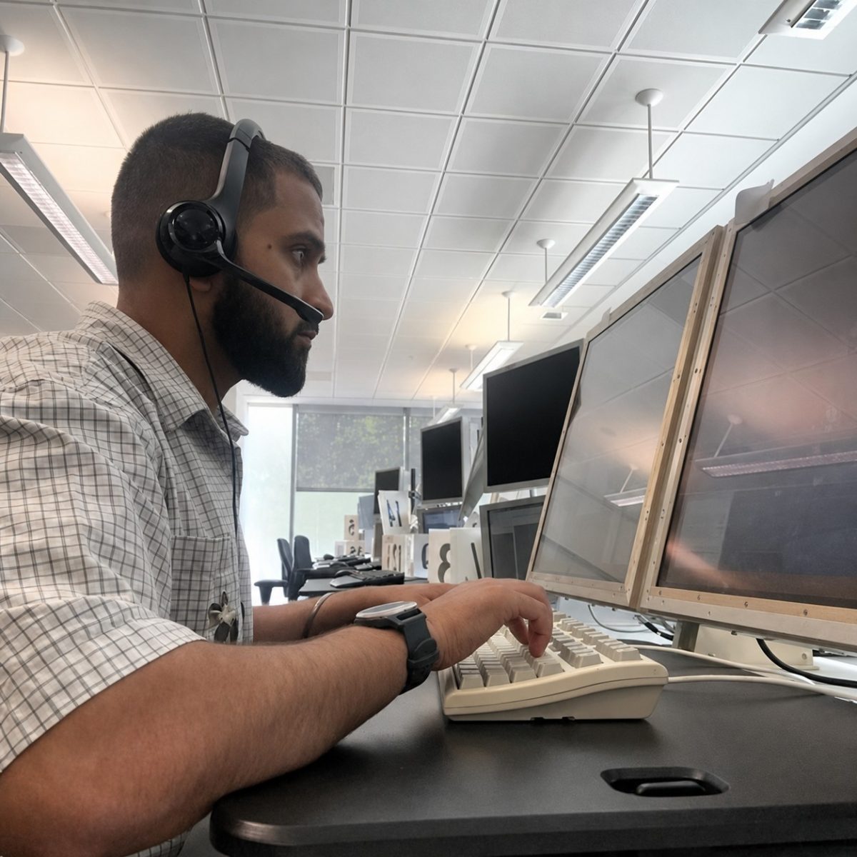 Testing Engineering Technician Arrun, sat at a computer wearing a headset, looking intently at the screen and typing on the keyboard.