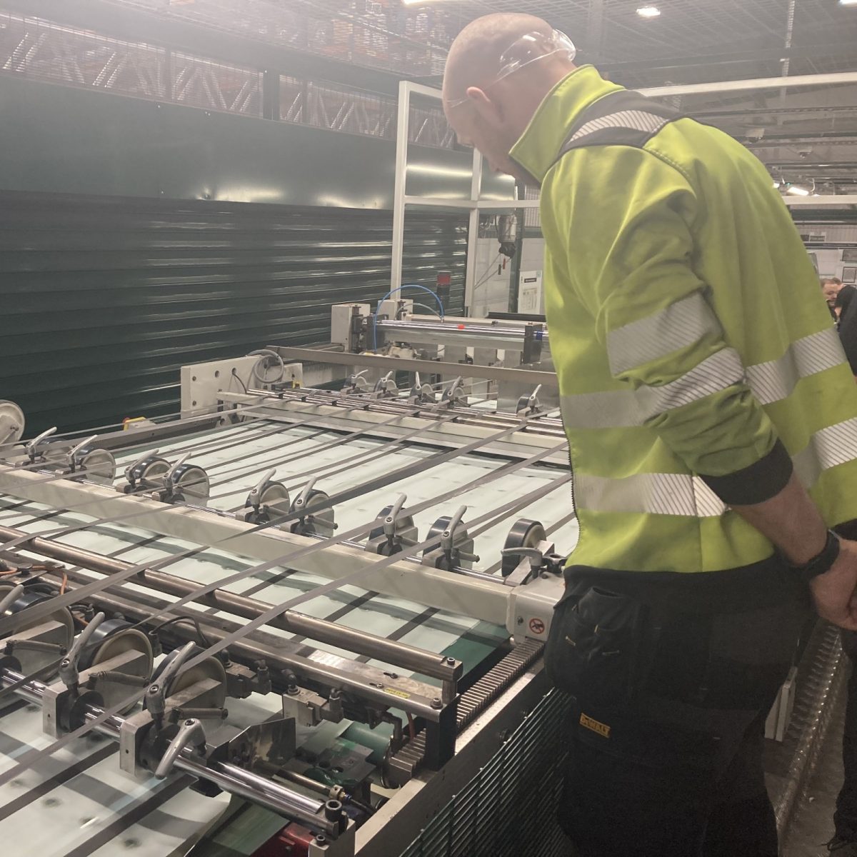 Print Technician Michael, wearing a hi-vis jacket, inspecting a large industrial machine, in a manufacturing workshop.